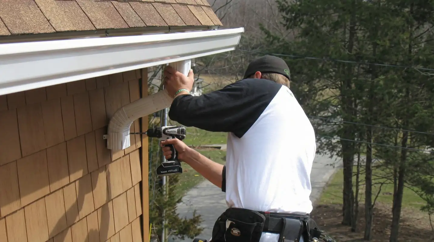 Professional contractor installing tan vinyl siding panels on a residential home exterior in Springfield, MO